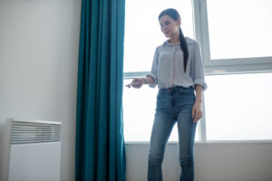 Female Aiming A Device At The Heater